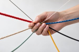 Eine Hand hält viele bunte Fäden